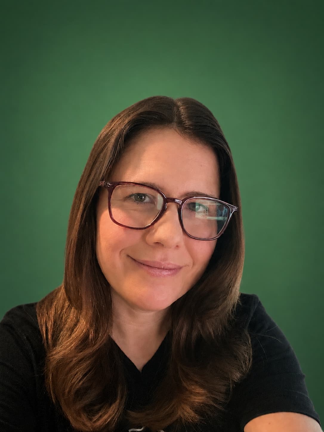 Headshot of Jen Ross, founder of Mercury Jane, wearing glasses and a black top against a verde green backdrop