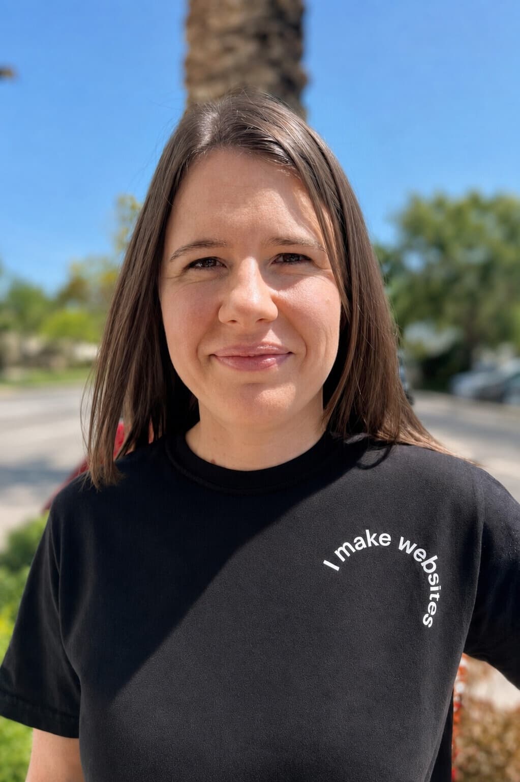 Jen Ross, founder of Mercury Jane, smiling outdoors in Mount Dora wearing a black t-shirt that reads 'I make websites'